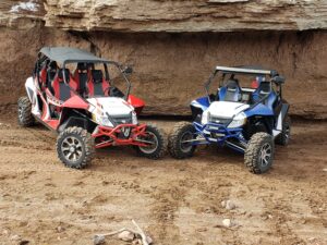 Two off road vehicles parked in a dirt area.