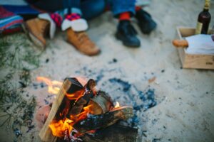 A fire is burning on the ground while people sit in front of it.