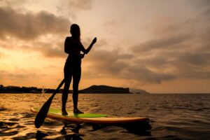 A woman is standing on a paddle board in the ocean.